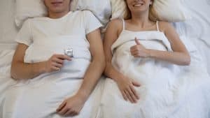 a couple in bed holding a condom